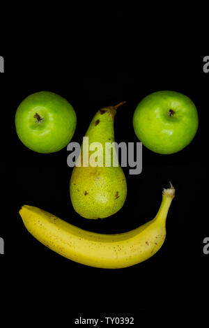 Smiling fruit face with apple eyes isolated on black background Stock Photo