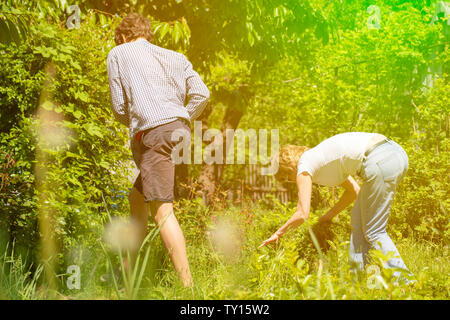 family od mother and her son work at the backyard of their spring cottage using tools Stock Photo