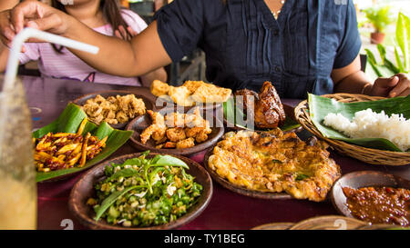 Tasty looking Indonesian food served on the table with a variety of chili sauces, rice, prawns, chicken and omlette. Travel and food concept image fro Stock Photo