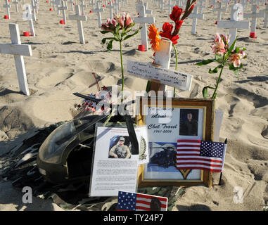 Flowers, photographs of Capt. Chester Troxel, and a model Blackhawk helicopter are pictured next to a cross as part of a Memorial Day display at the Arlington West Memorial Project in Santa Monica, California on May 29, 2011. Troxel was killed when his Blackhawk crashed at the beginning of the Iraq war. The beach memorial represents the 4,454 soldiers killed in Iraq and 2,393 killed in Afghanistan. The 12 mock caskets represent the soldiers killed this week: 10 in Afghanistan and 2 in Iraq.  UPI /Jim Ruymen) Stock Photo