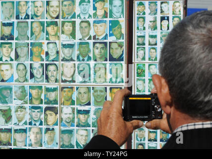 A man takes a picture of the faces of military members killed in action on display at the Arlington West Memorial Project in Santa Monica, California on May 29, 2011. The beach memorial represents the 4,454 soldiers killed in Iraq and 2,393 killed in Afghanistan. The 12 mock caskets (not pictured) represent the soldiers killed this week: 10 in Afghanistan and 2 in Iraq. At right is Robert Uranga.  UPI /Jim Ruymen) Stock Photo