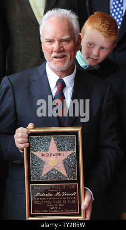 Malcolm McDowell, holds a replica plaque after he was honored with the 2,465th star on the Hollywood Walk of Fame during an unveiling ceremony in Los Angeles on March 16, 2012. Looking on at right is his son Beckett.   UPI/Jim Ruymen Stock Photo