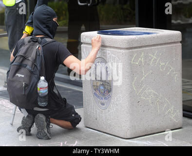 Hundreds of protesters, including family members of victims participate in march against police brutality and stop at the police station in Anaheim, California on July 21, 2013.  A protestor writes on a trash can in front of the entrance.  UPI/Lori Shepler Stock Photo