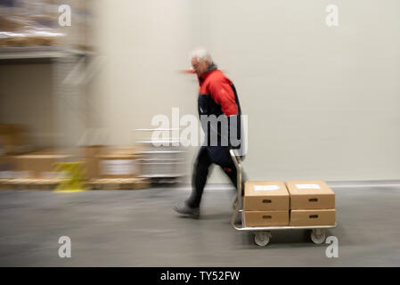 Wiesentheid, Germany. 25th June, 2019. Werner Beck, medical specialist for fresh plasma storage, transports blood plasma in cartons inside a warehouse of the Blutplasma Bank of the Bavarian Red Cross. The temperature in the hall is -42° C. (to dpa 'Heat in Germany - cold places in Bavaria') Credit: Nicolas Armer/dpa/Alamy Live News Stock Photo