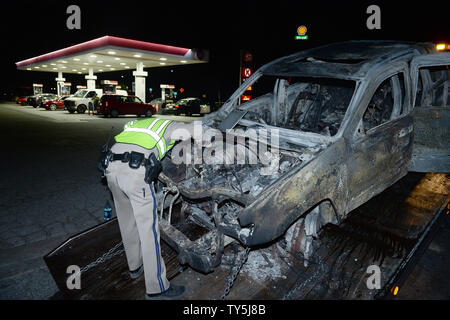 A California Highway Patrol officer examines one of 30 cars destroyed as a brush fire spread to vehicles trapped along interstate 15 in the Cajon Pass in San Bernardino County on July 17, 2015. The fast-moving wildfire jumped the busy I-15 freeway, the main roadway connecting Los Angeles and Las Vegas, setting several cars, homes and a big-rig on fire while torching nearly 4,000 acres of land.  Photo by Jim Ruymen/UPI Stock Photo