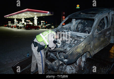 A California Highway Patrol officer examines one of 30 cars destroyed as a brush fire spread to vehicles trapped along interstate 15 in the Cajon Pass in San Bernardino County on July 17, 2015. The fast-moving wildfire jumped the busy I-15 freeway, the main roadway connecting Los Angeles and Las Vegas, setting several cars, homes and a big-rig on fire while torching nearly 4,000 acres of land.  Photo by Jim Ruymen/UPI Stock Photo