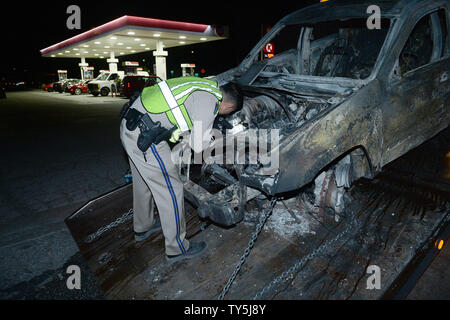 A California Highway Patrol officer examines one of 30 cars destroyed as a brush fire spread to vehicles trapped along interstate 15 in the Cajon Pass in San Bernardino County on July 17, 2015. The fast-moving wildfire jumped the busy I-15 freeway, the main roadway connecting Los Angeles and Las Vegas, setting several cars, homes and a big-rig on fire while torching nearly 4,000 acres of land.  Photo by Jim Ruymen/UPI Stock Photo