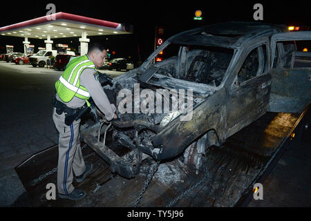 A California Highway Patrol officer examines one of 30 cars destroyed as a brush fire spread to vehicles trapped along interstate 15 in the Cajon Pass in San Bernardino County on July 17, 2015. The fast-moving wildfire jumped the busy I-15 freeway, the main roadway connecting Los Angeles and Las Vegas, setting several cars, homes and a big-rig on fire while torching nearly 4,000 acres of land.  Photo by Jim Ruymen/UPI Stock Photo