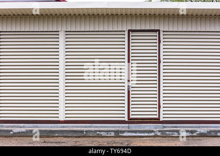 exterior view of warehouse with locked door. metal sheet louvers on wall for ventilation Stock Photo