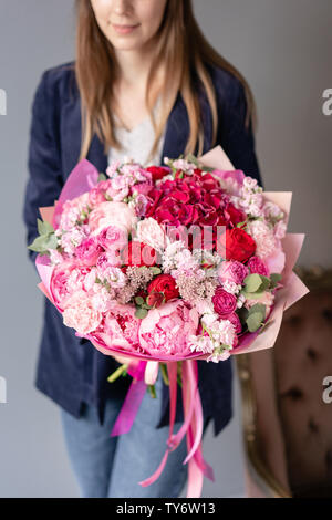 Pink peonies and red hydrangea. Beautiful bouquet of mixed flowers in woman hand. Floral shop concept . Handsome fresh bouquet. Flowers delivery. Red Stock Photo