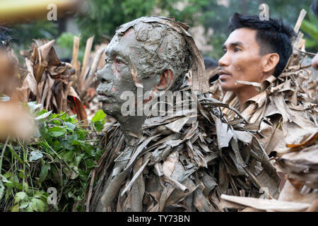 Devotees take part in the ‘Taong Putik’  or mud people festival in the town of Bibiclat,Aliaga,Nueva Ecija,Philippines.Held annually on the 24th June the century old religious festival honors the Christian Saint, John The Baptist. Before dawn those involved enter nearby rice fields adorning their bodies with mud & making cloaks made from torn banana leaves, twigs, and vines to emulate John the Baptist's appearance when he baptized Christ. Proceeding through the streets the procession is a form of penance On reaching their local Parish church a theatrical play is performed depicting the Life & Stock Photo