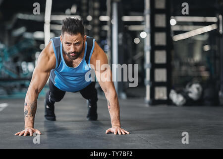 Concentrated muscular guy doing push up exercises Stock Photo