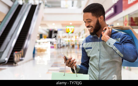 African american man with shopping bags using cellphone Stock Photo