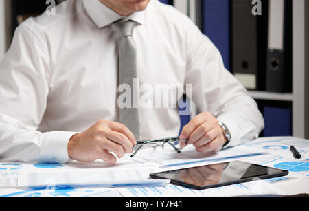 Businessman working with tablet pc, calculating, reading and writing reports. Office employee, table closeup. Business financial accounting concept. Stock Photo