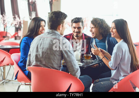 Funny friends laugh sitting at a table in a cafe. Meeting friends in your free time. Stock Photo