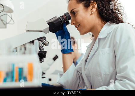 Joyful happy smart woman using the microscope Stock Photo
