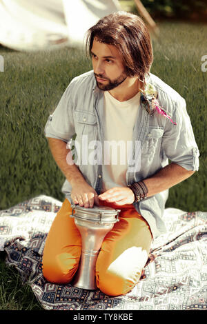 Nice long haired man playing music in the park Stock Photo