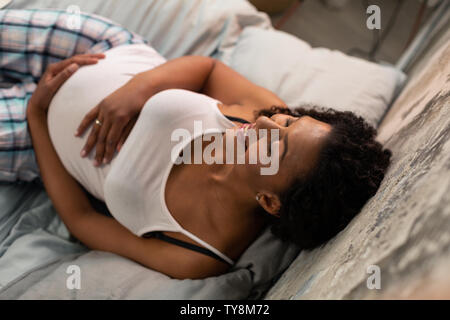 Smiling pregnant woman laying on her bed. Stock Photo