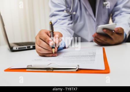 Doctor in gown uniform using a pen write on medical chart Stock Photo
