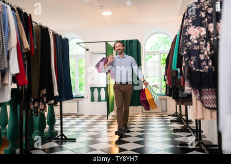 Happy man of 30s walking with packages in the showroom. Stock Photo
