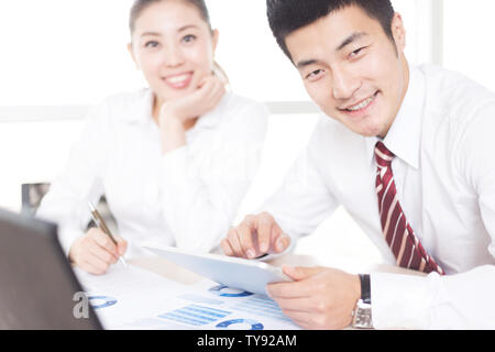handsome chinese businessman and pretty chinese businesswoman with digital tablet in modern office Stock Photo