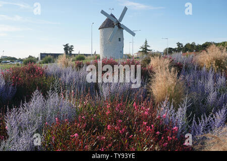 colorful flower garden in front of a white stone windmill Stock Photo