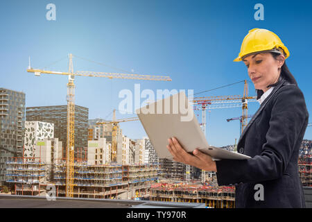 Woman engineer using laptop on building structure and blue sky background Stock Photo