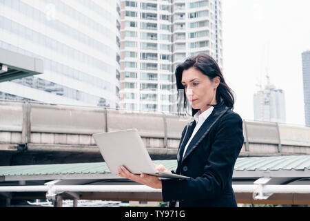 Smart businesswoman stand using laptop in the city Stock Photo