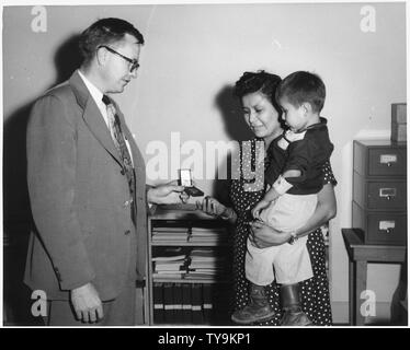 [Navajo mother holding child being given a medal by school superintendent.] Stock Photo