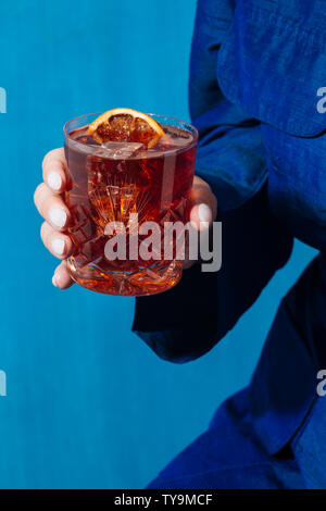Woman and Negroni cocktail, with gin, bitter and vermouth. Colorful and trendy. Stock Photo
