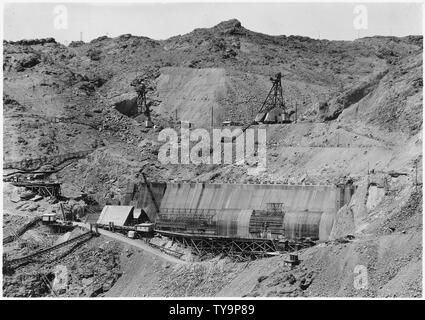 Nevada spillway and adjacent terrain as seen from Arizona rim of Black Canyon. Head towers for Six Companies, Inc., cableways Nos. 5 and 6 seen on bench above spillway structure. Downstream is to the left in the photograph.; Scope and content:  Photograph from Volume Two of a series of photo albums documenting the construction of Hoover Dam, Boulder City, Nevada. Stock Photo