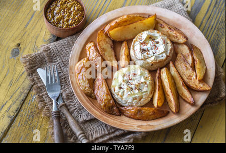 Baked Camembert cheese with roasted potatoes on the plate Stock Photo