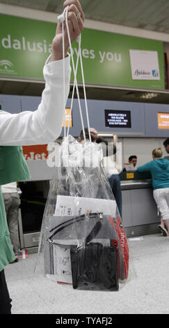 Following yesterday's terror alert, a female passenger at Gatwick airport holds up a bag containing all her travel documents to conform to new security rules banning all hand luggage being taken on board planes on August 11, 2006.  All travellers are only allowed to carry essential documents,reading glasses,medicine etc.  All electrical goods such as laptops or cellular phoned have to be put in their main luggage. Twenty-four people were arrested by police in the early hours of Thursday morning suspected of plotting to blow up airplanes on route for the United States.  All passengers are being Stock Photo