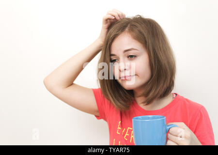 Portrait of young caucasian woman girl, yawning, tired or sleepy with bushy disheveled hair holding a mug of coffee Stock Photo