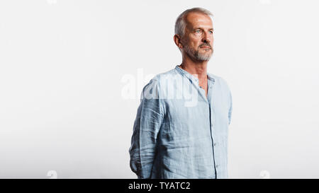 Senior man isolated on white background. Man standing with his hands behind him looking away. Stock Photo