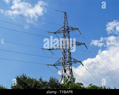 Power line pylon and high-voltage wires with glass fuses against a bright blue sky with white clouds on a sunny day. Power industry and electricity. Stock Photo