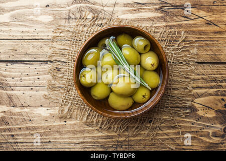 Green olives in wooden bowls on wooden table. Top view with space for text Stock Photo