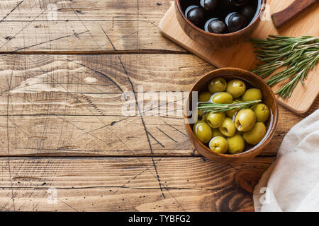 Black and green olives in wooden bowls on wooden table. Top view with space for text Stock Photo