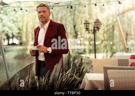 Bearded mature man wearing stylish jacket drinking coffee outside Stock Photo