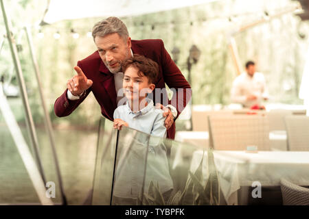 Handsome cute son standing near father on summer terrace Stock Photo