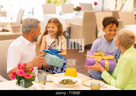 Loving boy and girl giving present boxes to grandchildren Stock Photo