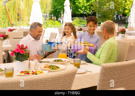 Beaming children giving their grandparents presents Stock Photo