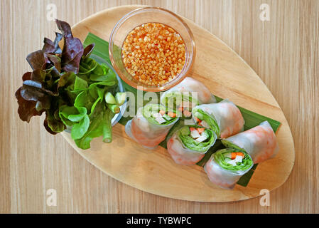 Prawn and fresh vegetable spring rolls served with green salad on a wooden plate Stock Photo