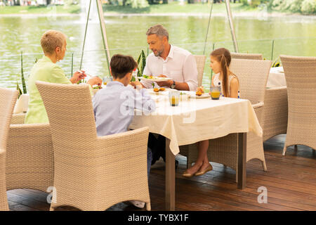 Grandchildren enjoying breakfast near lake with grandparents Stock Photo