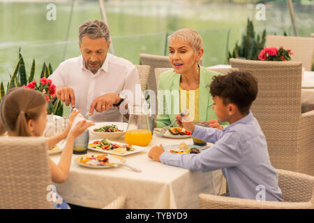 Two children and grandparents enjoying nice morning in restaurant Stock Photo