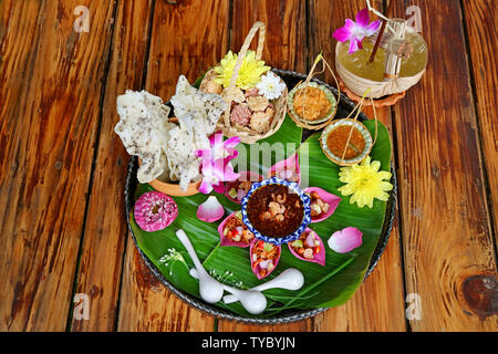 Thai Appetizer Set of Fresh Lotus Petal Wrapped and Crispy Fried Rice Cakes with Calamansi Citrus Juice Served on Wooden Table Stock Photo