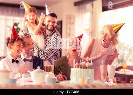 Aged woman blowing candles while celebrating birthday Stock Photo