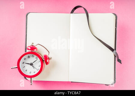 Alarm clock with notepad on bright pink table. Performance, work or study concept, Creative flatlay copy space above Stock Photo