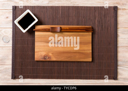 Empty rectangular wooden plate with chopsticks for sushi and soy sauce on wood background. Top view with copy space. Stock Photo