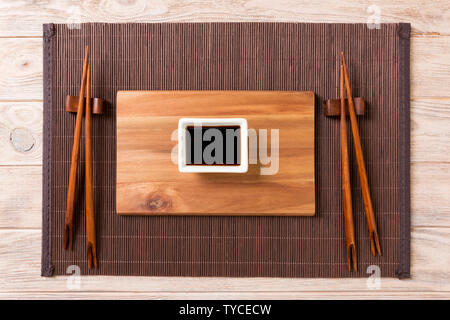 Empty rectangular wooden plate with chopsticks for sushi and soy sauce on wood background. Top view with copy space. Stock Photo